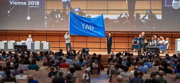 2018년 비엔나에서 개최된 제30차 IAU 총회에서  강혜성 교수(조직위원장)와 박명구 교수(한국천문학회장)가 대회기를 이양받고 있다.